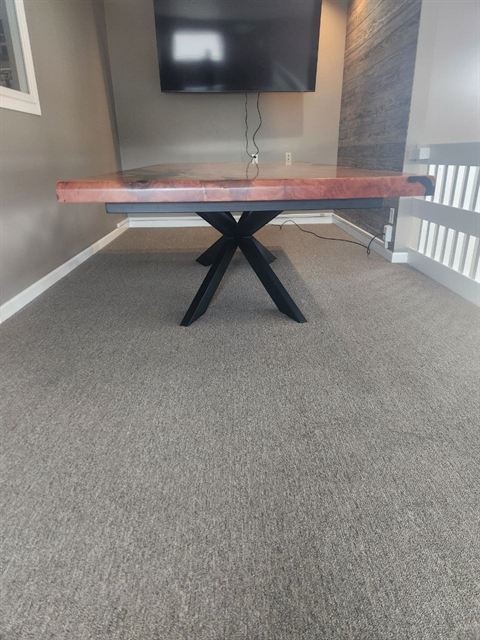 The blackened steel base of Black Willow, a splayed cross pedestal, seen at floor level