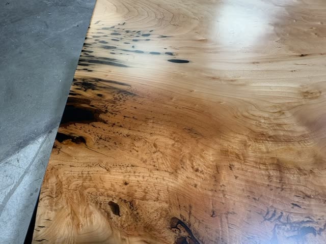 Black Willow surface at a low angle, the figured willow grain under a glass polyurethane finish